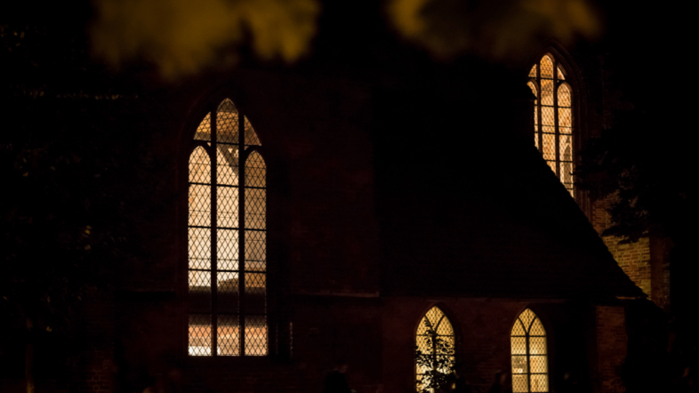 Erleuchtete Kirchenfenster bei Nacht.