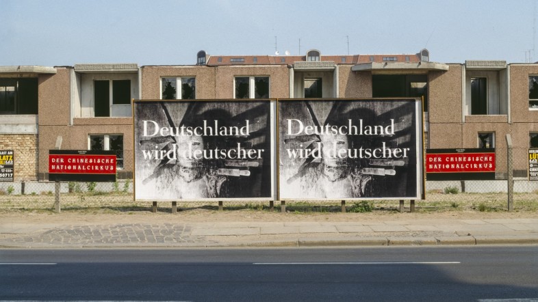 Fotografie von zwei Plakaten, die vor einem Hausblock stehen. Das Plakat ist schwarz weiß und darauf ist "Deutschland wird deutscher" nieder geschrieben.