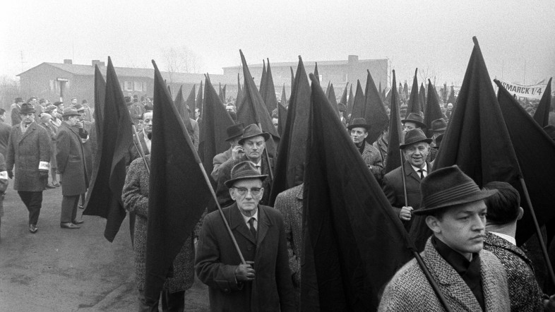 Schwarzweiß-Fotografie einer Demonstration, die Männer mit schwarzen Flaggen zeigt. Teil der Ausstellung Streik! im Museum der Arbeit.